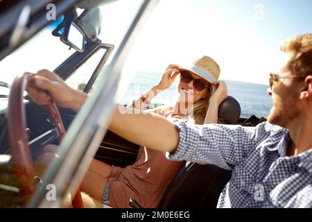 Ein Wochenendausflug. Ein glückliches junges Paar, das an einem schönen Sommertag in einem Cabrio fährt. Stockfoto