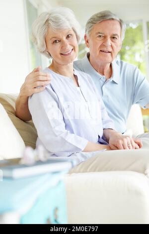 Er ist die Liebe meines Lebens. Ein liebevolles Seniorenpaar, das eine andere Gesellschaft in seinem Wohnzimmer genießt. Stockfoto