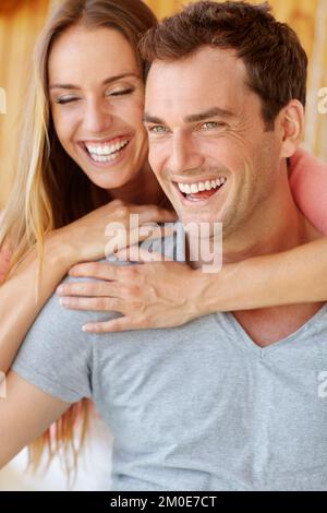 Ich habe meine Seelenverwandte gefunden. Ein glückliches junges Paar, das auf der Couch sitzt und sich liebevoll umarmt. Stockfoto