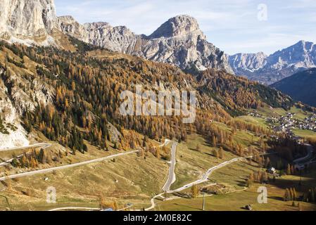 Schmale Asphaltstraße führt zu einem sonnigen Herbsttag in den italienischen Dolomiten Stockfoto