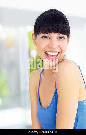 Sie hat eine sonnige Einstellung. Eine reizende junge Frau, die lacht und ein großes Lächeln schenkt. Stockfoto