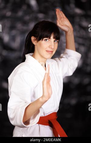 Hübsch, aber hart. Porträt einer jungen Frau, die Karate in ihrem gi praktiziert. Stockfoto