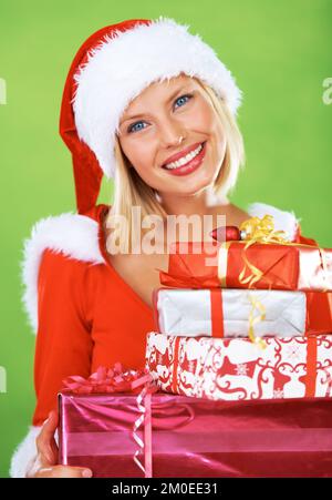 Bei Weihnachten geht es nur ums Geben. Hübsche blonde Frauen in einem Weihnachtskostüm mit einem Stapel bunter Geschenke. Stockfoto