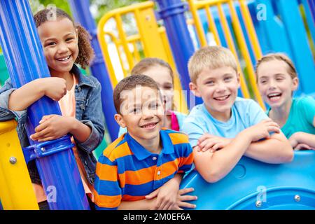 Zusammen aufwachsen. Eine multiethnische Gruppe glücklicher Kinder, die in einem Dschungelstudio in einem Spielpark spielen. Stockfoto