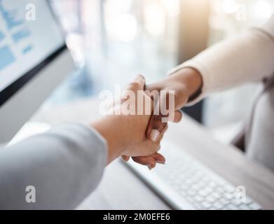 Nahaufnahme von zwei Geschäftsfrauen, die während eines Meetings in einem Büro die Hände über einen Schreibtisch schütteln. Mitarbeiter, die eine erfolgreiche Beförderung, ein erfolgreiches Geschäft und eine erfolgreiche Fusion abschließen Stockfoto