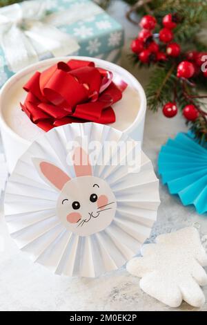 Wintergrußkarte. Weihnachtshintergrund mit Weihnachtsbaum, Geschenkboxen und Symbol des Jahres Mond, chinesischer Kalender, Jahr des Hasen. Stockfoto