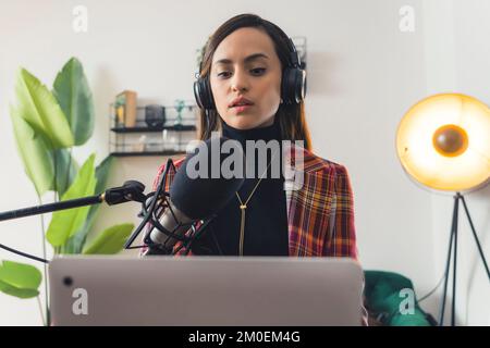 Charmantes Radio-Moderatorin, das mit ihrem Laptop, dem Medium-Shot-Radio und Kommunikationskonzepten sendet und arbeitet. Hochwertiges Foto Stockfoto