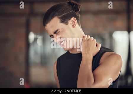 Bodybuilder hat einen Nackenkrampf im Fitnessstudio. Fit, junger Mann mit Nackenschmerzen im Fitnessstudio. Sportlicher Muskelmann mit Nackenschmerzen im Fitnessstudio. Starker Mann Stockfoto