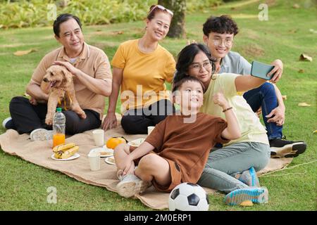 Eine dreiköpfige Familie macht Selfie beim Picknick im Park Stockfoto