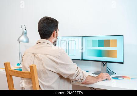 Grafikdesigner, der in einer Telefon-App mit seinem Computer und dem digitalen Tablet in einem modernen Heimbüro arbeitet. Stockfoto