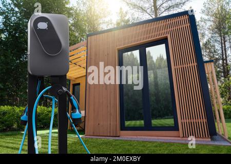 Ein hölzernes Landhaus im Wald mit einer Ladestation für Elektroautos Stockfoto