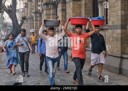 Träger mit Fischteller auf dem Kopf, vor dem Chhatrapati Shivaji Maharaj Terminus (CMST) in Mumbai, Indien, um die Tabletts mit dem Zug zu transportieren Stockfoto