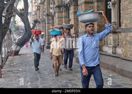 Gepäckträger mit Fischteller auf dem Kopf, vor dem Chhatrapati Shivaji Maharaj Terminus (CMST) in Mumbai, Indien, um die Tabletts mit dem Zug zu transportieren Stockfoto