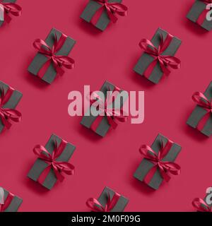 Nahtloses Muster aus schwarzem Geschenk mit Schleife in Viva Magenta auf einfarbigem Hintergrund. Trendige Farbe von 2023 - Viva Magenta. Stockfoto