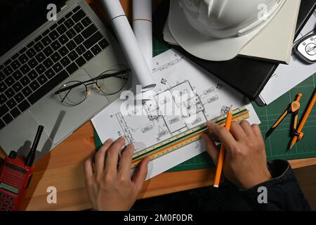 Ingenieur oder Architekt, der mit Bauplänen arbeitet und Entwicklungsdetails an der Workstation plant Stockfoto