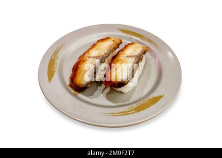 Gestanzte Stücke von Unagi-Sushi (gegrillter Aal), die in grauen Tellern serviert und auf weiß isoliert gelegt werden. Stockfoto