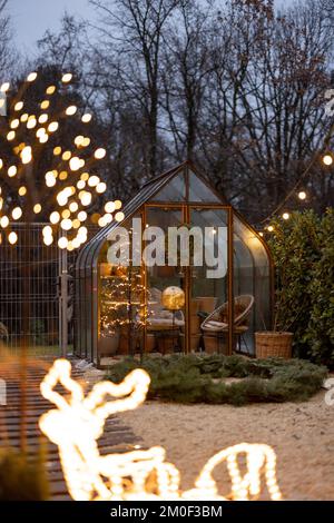 Wunderschöner Hinterhof mit altem Gewächshaus und Weihnachtskranz im Winter Stockfoto