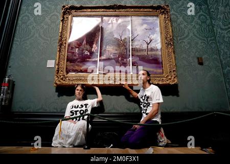 Aktenfoto vom 04.07/22 von Demonstranten der Just Stop Oil Climate Protestgruppe, die ihre Hände an den Rahmen von John Constable's The Hay Wain klebten, nachdem sie das Gemälde zuerst mit ihrem eigenen Bild in der National Gallery, London, bedeckt hatten. Hannah Hunt und Eden Lazarus sind am Westminster Magistrates' Court erschienen, angeklagt, das Hay Wain Gemälde und den Rahmen in der National Gallery kriminell beschädigt zu haben. Ausgabedatum: Dienstag, 6. Dezember 2022. Stockfoto