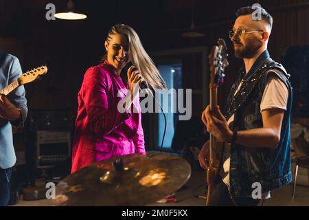 Musikband mit einer Sängerin, die einen Song in einem Studio aufnimmt. Hochwertiges Foto Stockfoto