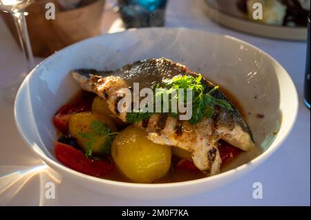 Provenzalische Küche, gegrilltes Weißfischfilet vom Seabarsch, serviert mit Kartoffeln, Tomaten und Bouillabaisse-Fischjus im französischen Restaurant Stockfoto