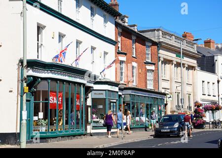 Blick auf die Einkaufsstraße High Street im Stadtzentrum mit Shoppers zu Fuß, Sidmouth, Devon, Großbritannien, Europa. Stockfoto