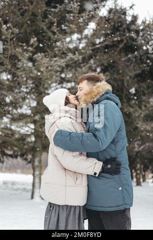 Ein Paar küsst sich im verschneiten Wald Stockfoto