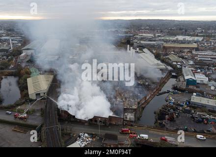 Feuerwehrleute am Tatort eines Großschadens in einer verlassenen Fabrik in Lower Horseley Fields, Wolverhampton, wo ein Brand mehrere Fabrikeinheiten erfasst hat, wobei mehr als 100 Feuerwehrleute anwesend waren, um den Brand abzufangen. Foto: Dienstag, 6. Dezember 2022. Stockfoto