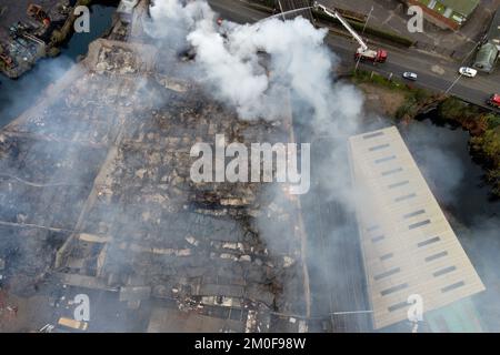 Feuerwehrleute am Tatort eines Großschadens in einer verlassenen Fabrik in Lower Horseley Fields, Wolverhampton, wo ein Brand mehrere Fabrikeinheiten erfasst hat, wobei mehr als 100 Feuerwehrleute anwesend waren, um den Brand abzufangen. Foto: Dienstag, 6. Dezember 2022. Stockfoto