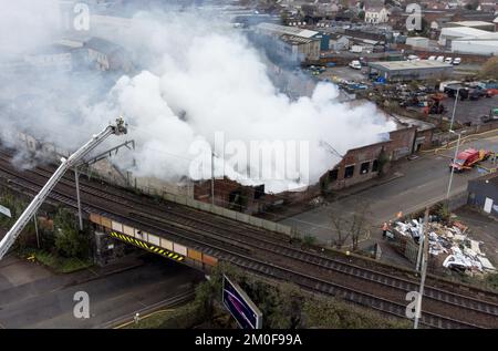 Feuerwehrleute am Tatort eines Großschadens in einer verlassenen Fabrik in Lower Horseley Fields, Wolverhampton, wo ein Brand mehrere Fabrikeinheiten erfasst hat, wobei mehr als 100 Feuerwehrleute anwesend waren, um den Brand abzufangen. Foto: Dienstag, 6. Dezember 2022. Stockfoto