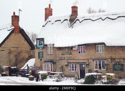 Das Bell Public House. Eine verschneite Szene. Ein altes Gasthaus oder öffentliches Haus im Dorf Odell, Bedfordshire, Großbritannien. Stockfoto