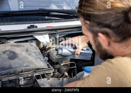 Mann, der Öl in den Motor eines Lieferwagens einfüllt Stockfoto