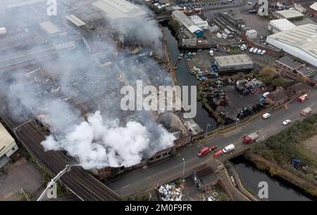 Feuerwehrleute am Tatort eines Großschadens in einer verlassenen Fabrik in Lower Horseley Fields, Wolverhampton, wo ein Brand mehrere Fabrikeinheiten erfasst hat, wobei mehr als 100 Feuerwehrleute anwesend waren, um den Brand abzufangen. Foto: Dienstag, 6. Dezember 2022. Stockfoto