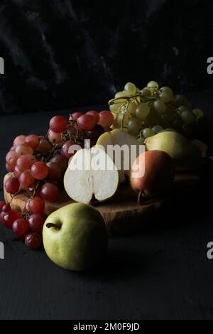 Trauben- und Birnenfrüchte auf schwarzem Hintergrund Stockfoto