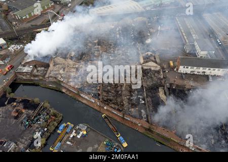 Feuerwehrleute am Tatort eines Großschadens in einer verlassenen Fabrik in Lower Horseley Fields, Wolverhampton, wo ein Brand mehrere Fabrikeinheiten erfasst hat, wobei mehr als 100 Feuerwehrleute anwesend waren, um den Brand abzufangen. Foto: Dienstag, 6. Dezember 2022. Stockfoto