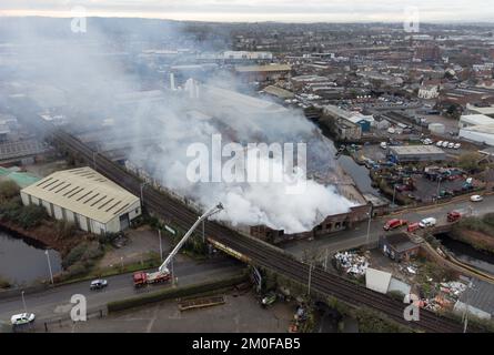 Feuerwehrleute am Tatort eines Großschadens in einer verlassenen Fabrik in Lower Horseley Fields, Wolverhampton, wo ein Brand mehrere Fabrikeinheiten erfasst hat, wobei mehr als 100 Feuerwehrleute anwesend waren, um den Brand abzufangen. Foto: Dienstag, 6. Dezember 2022. Stockfoto