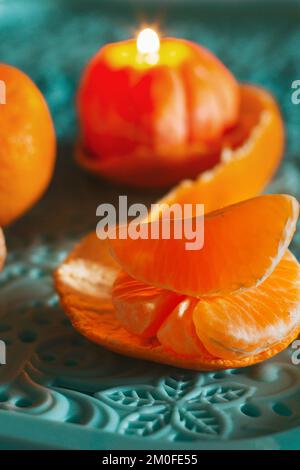 Eine brennende Kerze in Form einer Mandarine. Weihnachtsaufführung. Wunderschöne handgemachte Kerzen. Stockfoto