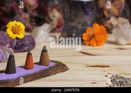 Räucherkegel auf Steinplatte mit Steinkristallen und Blumen Stockfoto