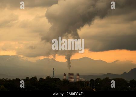 Zeitraffer eines Kohlekraftwerks und Dampf, der bei Sonnenuntergang aus den Stapeln strömt. Steinkohlekraftwerk bei Nacht aus der Vogelperspektive. Industrielandschaft Stockfoto