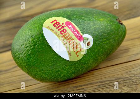 Hamburg, Deutschland - Dezember 6 2022: Avocado und Label mit Reifepunkt auf Holz - Avocado und Etikett mit Reifungspunkt auf Holz Stockfoto