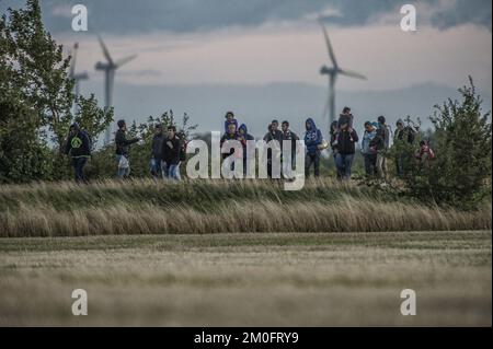 Die erste große Gruppe von Flüchtlingen und Einwanderern hat die dänische Grenze in Rødby im Süden Seelands überquert. Nach Angaben der Polizei von Süuseeland und Lolland-Falster kamen über zwei Fähren aus Puttgarden in Deutschland etwa 170 Flüchtlinge nach Rødby. Einige Migranten flohen vor der Polizei in Rødby, wurden aber angehalten und in Bussen abgeholt. Die überwiegende Mehrheit der registrierten Migranten kommt aus Syrien, und diejenigen, deren Asylverfahren in Dänemark vor Gericht gestellt werden, werden in das Flüchtlingslager Sandholmlejren entsandt. Per Rasmussen / Polfoto Flygtninge på flugt fra politiet ved Rødbyhavn. Ca Hunderrede Stockfoto