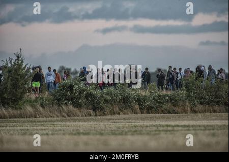 Die erste große Gruppe von Flüchtlingen und Einwanderern hat die dänische Grenze in Rødby im Süden Seelands überquert. Nach Angaben der Polizei von Süuseeland und Lolland-Falster kamen über zwei Fähren aus Puttgarden in Deutschland etwa 170 Flüchtlinge nach Rødby. Einige Migranten flohen vor der Polizei in Rødby, wurden aber angehalten und in Bussen abgeholt. Die überwiegende Mehrheit der registrierten Migranten kommt aus Syrien, und diejenigen, deren Asylverfahren in Dänemark vor Gericht gestellt werden, werden in das Flüchtlingslager Sandholmlejren entsandt. Per Rasmussen / Polfoto Flygtninge på flugt fra politiet ved Rødbyhavn. Ca Hunderrede Stockfoto