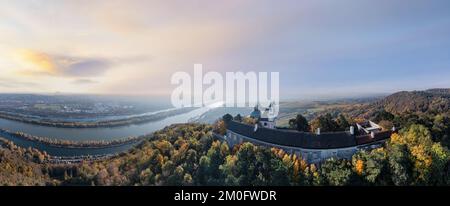 Wiener Leopoldsbergkirche auf dem Hügel Leopoldsberg während eines malerischen Sonnenaufgangs im Herbst. Wunderschöne Aussicht auf die Donau. Stockfoto