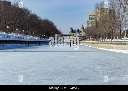 Ein Blick auf die Leute, die während Winterlude auf dem Rideau Canal mit der Skyline von Ottawa skaten Stockfoto