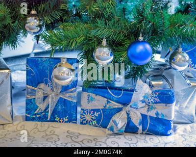 Verzierte Geschenkboxen mit dekorativen Kugeln unter dem weihnachtsbaum Stockfoto