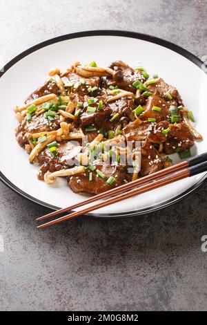 Japanisches Essen scharfes Teriyaki-Rindersteak in Sauce mit Pilzen auf dem Teller auf dem Tisch. Vertikal Stockfoto