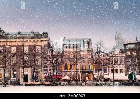 Winterblick mit Schneefall auf den zentralen historischen Platz Plein neben dem Binnenhof mit Bars und Restaurants im antiken Stadtzentrum von Den Haag Stockfoto