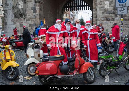 Mitglieder der Vespa-Motorroller-Clubs, die sich während einer Fahrt durch die Stadt Köln als Santas verkleidet haben. Die Roller sind beleuchtet und für Chri dekoriert Stockfoto