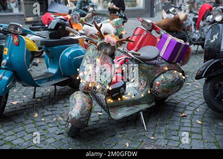 Mitglieder der Vespa-Motorroller-Clubs, die sich während einer Fahrt durch die Stadt Köln als Santas verkleidet haben. Die Roller sind beleuchtet und für Chri dekoriert Stockfoto