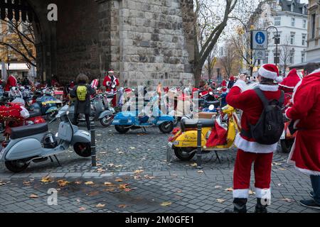 Mitglieder der Vespa-Motorroller-Clubs, die sich während einer Fahrt durch die Stadt Köln als Santas verkleidet haben. Die Roller sind beleuchtet und für Chri dekoriert Stockfoto