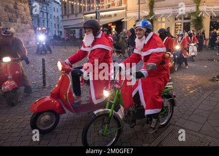 Mitglieder der Vespa-Motorroller-Clubs, die sich während einer Fahrt durch die Stadt Köln als Santas verkleidet haben. Die Roller sind beleuchtet und für Chri dekoriert Stockfoto